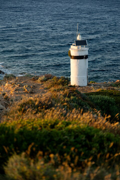 Lighthouse by the sea at golden sunset