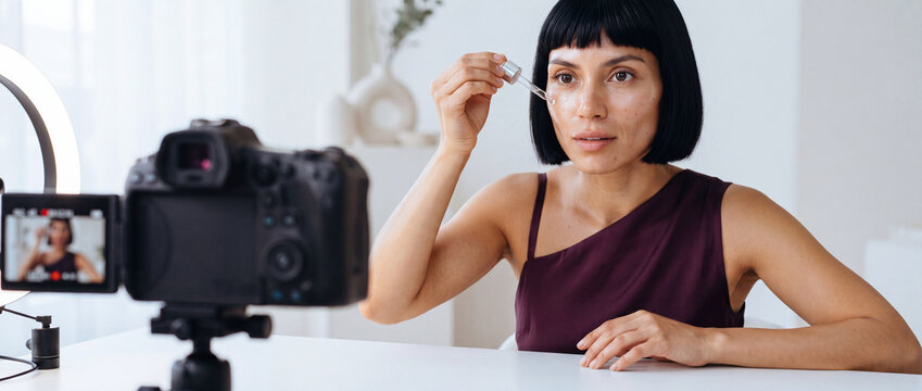 Beauty blogger applying facial serum on camera during a video tutorial recording in a bright studio with a ring light for cosmetic review, vlog content, and skincare marketing