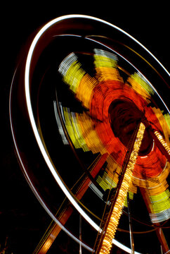 Spinning ferris wheel creating vibrant light patterns