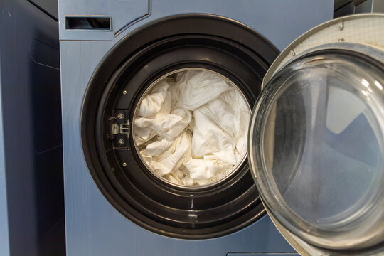 Open front load washing machine with white laundry inside