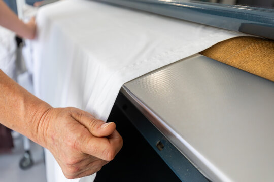 Hands pulling fabric from heat press in textile workshop