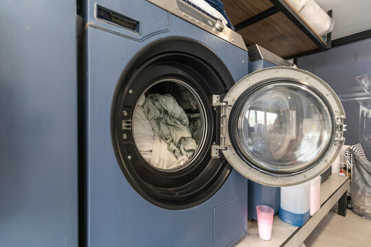 Open front load washing machine with laundry in utility room