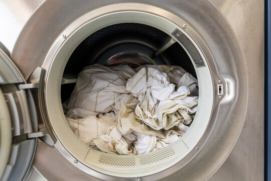 Open washer with white laundry inside, home cleaning concept
