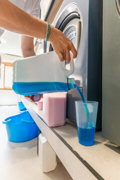 Person measuring laundry detergent beside washing machine