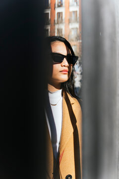 Stylish woman in sunglasses amidst city shadows