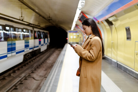 Woman using smartphone in urban metro station
