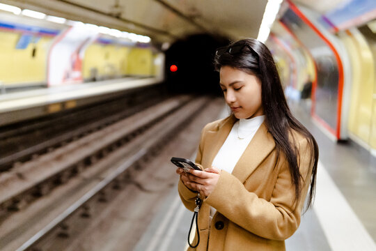 Woman using smartphone in urban subway station
