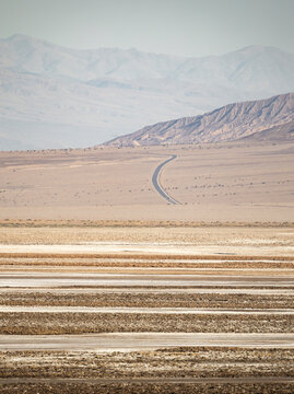 Empty desert highway crossing Death Valley salt flat