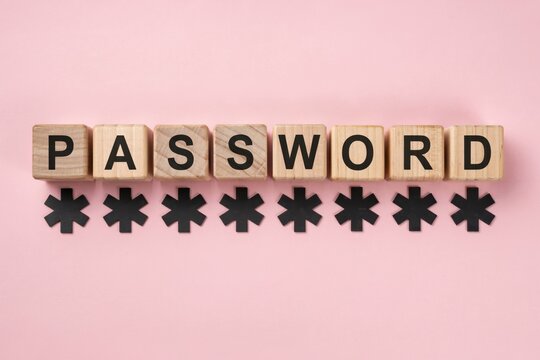 Wooden blocks spelling password with black asterisk symbols on pink background representing cybersecurity and account safety