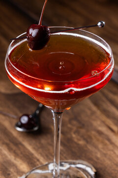 Closeup of a drop on top of a whiskey manhattan served on a rustic wooden background