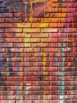 Colorful graffiti paint drips on weathered brick wall
