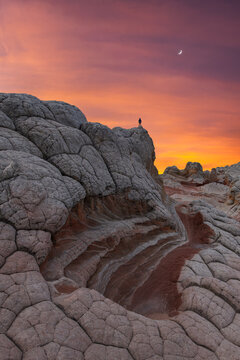Lone hiker on White Pocket sandstone at sunset sky