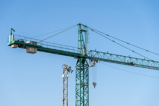 Green construction crane with clear blue sky background