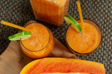 Homemade papaya smoothie in glasses and a glass pitcher with lime garnish. Fresh tropical fruit beverage for healthy breakfasts, summer drinks and natural nutrition. © Anna Zaro