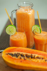 Papaya smoothie served in glasses and a glass pitcher with lime slices and drinking straws. Tropical fruit beverage rich in natural flavour, perfect for healthy breakfasts and summer refreshments. © Anna Zaro