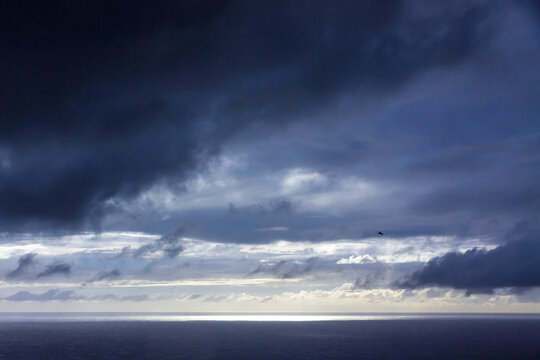 Dramatic storm clouds over the Atlantic Ocean near Sao Miguel Island, Azores, Portugal, with dark sky and rugged volcanic coastline creating a moody seascape