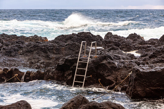 Natural ocean swimming pool at Ponta da Ferraria on the volcanic coast of Sao Miguel Island, Azores, Portugal, with Atlantic waves and dramatic evening sky