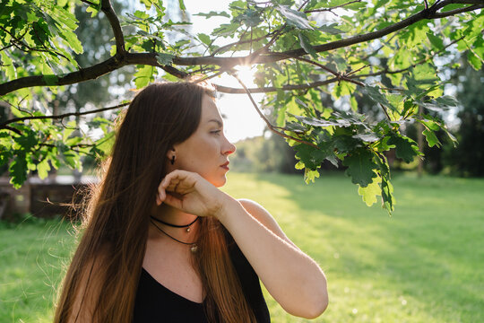 Woman enjoying nature at sunset under lush tree