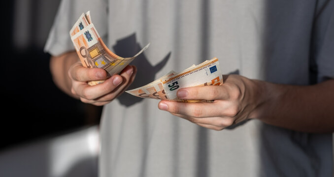Person holding two stacks of fifty euro banknotes