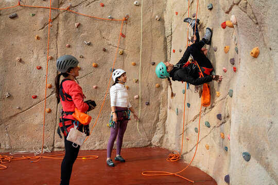 Women climb indoor rock wall during caving training