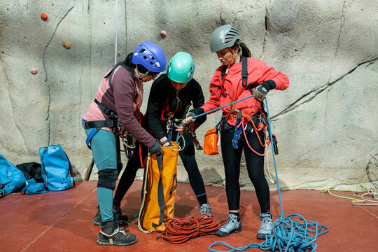 Women prepare climbing rope equipment at indoor training wall