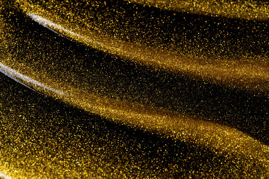 Gold oil texture with shimmering cosmetic liquid swirls