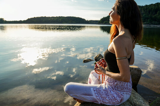 Woman meditating by a calm lake at sunrise for balance