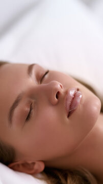 Sleeping woman with clear dental guard, close up side view, soft white background, calm skin, closed eye, relaxed face, copy space