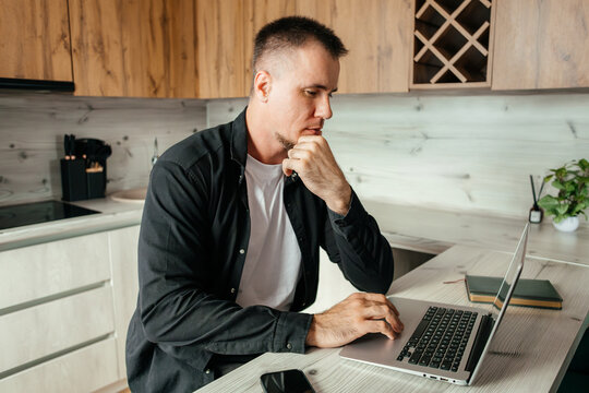 Man working remotely on laptop in a kitchen setting