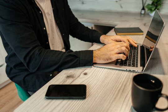 Remote work scene with man typing on laptop
