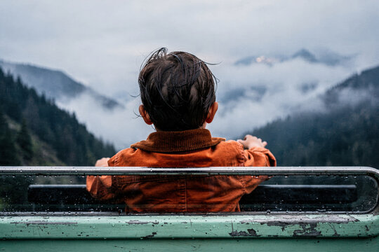 Boy Gazing at Misty Mountains from Vehicle Window