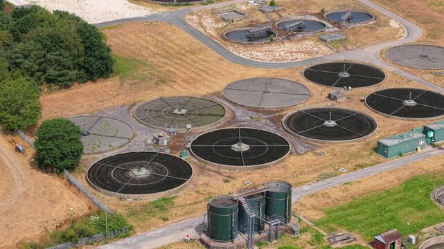 Close up aerial view of trickling filter beds, rotating spray arms, and gravel media at water treatment plant