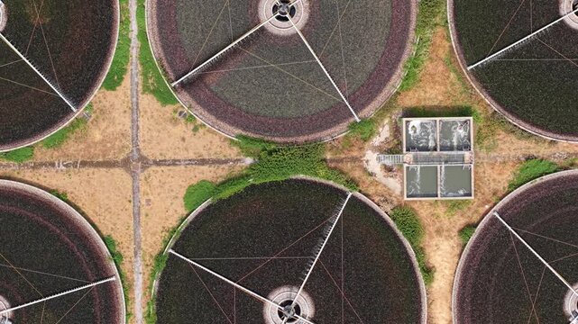 Close up aerial view of water treatment plant trickling filter beds and spray arms in UK