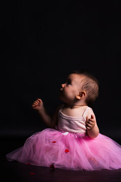 Curious baby girl wearing a pink tutu looking up