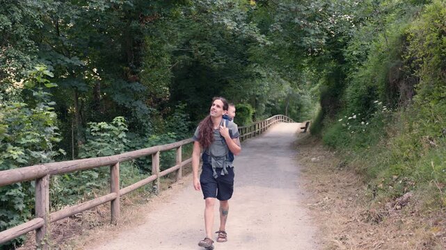 Father with baby carrier hiking in the woods with their dog