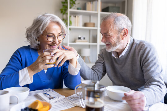Happy senior couple enjoying breakfast and showing affection at home
