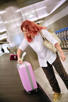 Woman retrieving luggage at airport baggage claim