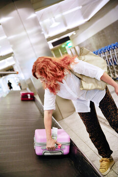 Woman retrieving luggage at airport baggage claim