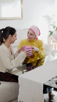 Daughter giving a gift to mother with cancer during family celebration