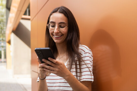 Young woman smiling while using phone outdoors