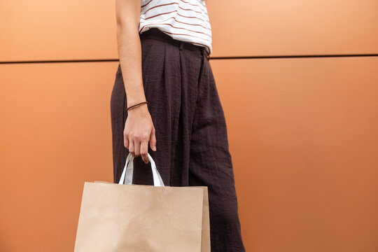 Woman carrying shopping bag against brown wall