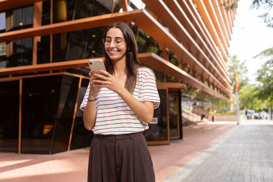 Woman smiling at smartphone in urban setting