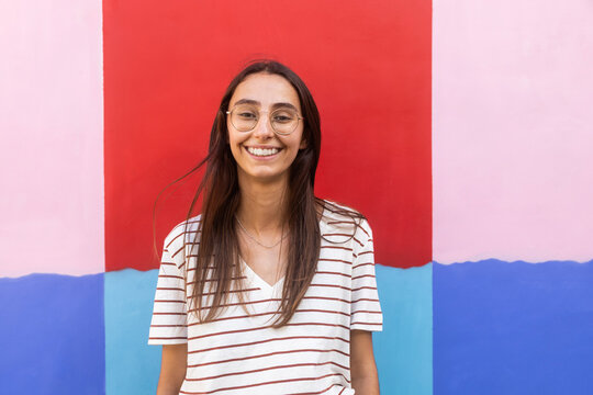 Young woman smiling against colorful wall