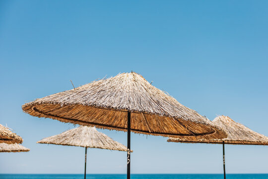 Thatched beach umbrella under clear blue summer sky
