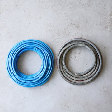 Coil of blue polyethylene tubing and grey lead pipe on concrete floor