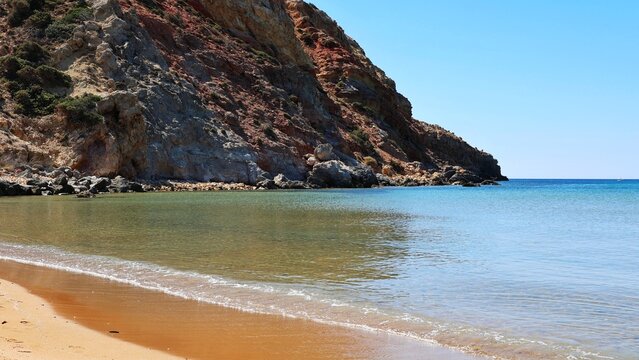 Golden sand beach and red cliffs at Provatas, Milos, Greece