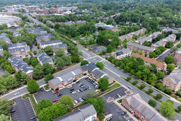 Obraz premium Aerial view of a green suburban neighborhood in Fairfax, VA, USA. Features brick townhouses, tree-lined streets, parking lots, and light traffic. Ideal for real estate marketing materials.
