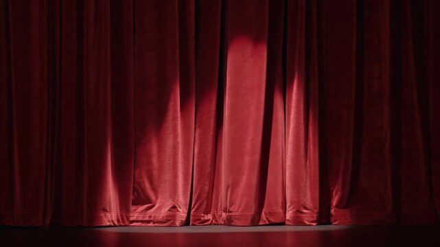 Static shot of closed red velvet stage curtains with subtle shifting spotlights on proscenium theater stage interior awaiting curtain rise