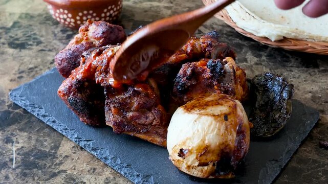 Pouring barbecue sauce on grilled pork ribs with roasted onion and tortillas
