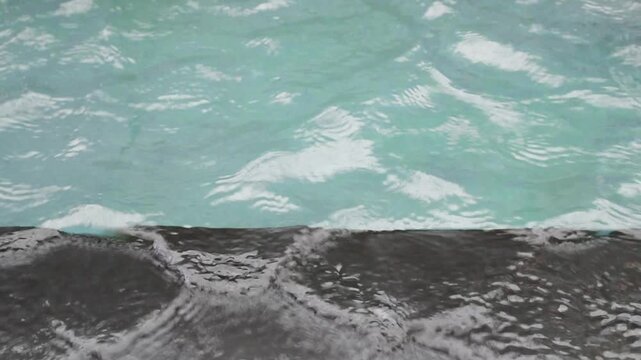 overflow turquoise ripple splashing over black marble pool edge, luxury spa relaxing